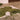 A large green textured rug or textile laid out on a white sheet on a concrete floor, with matching green rope or cord scattered around it in an indoor studio or gallery space.