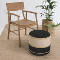 Wooden chair and striped ottoman on a textured floor with plants in the background