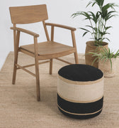 Wooden chair and striped ottoman on a textured floor with plants in the background
