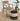 Wooden chair and striped ottoman on a textured floor with plants in the background
