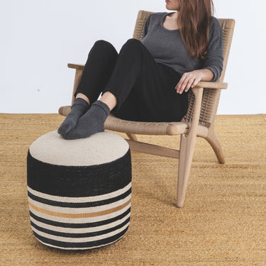 Person sitting on a chair with a striped ottoman in front