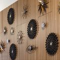 Decorative George Nelson for Vitra wall clocks with black and gold floral patterns on a wooden panel.
