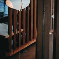 Modern floor lamp with a wooden base and white shade in a room setting.