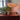 Table lamp with a warm glow on a wooden surface next to a plant