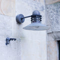 Wall-mounted nyhavn light with patina on outdoor light fixture on a stone building