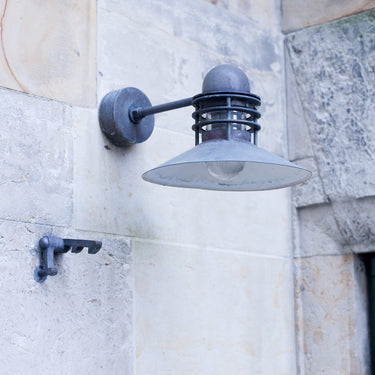 Wall-mounted nyhavn light with patina on outdoor light fixture on a stone building