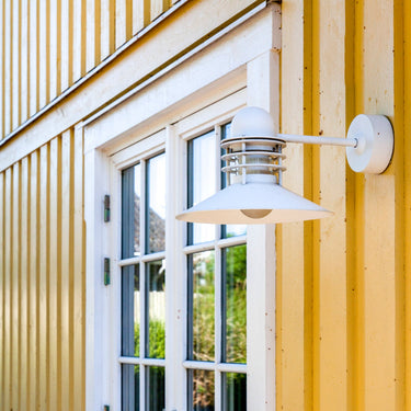 White danish outdoor wall light fixture on a yellow building exterior.