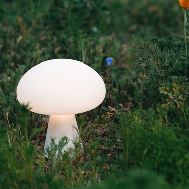 Mushroom-shaped lamp in a grassy field with flowers