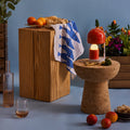 Decorative setting with a wooden block, cork table, fruits, and flowers against a blue background