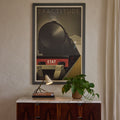 Wooden dresser with marble top, vintage 1950s italian lamp, and plant against a wall with a framed poster.