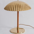 Gold table lamp with pleated shade on a light gray background