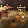 Various table lamps on a wooden floor and table against a dark wall.