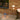 Outdoor setting with table lamps on a wooden deck against a brick wall.