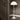 White 70s floor lamp against a dark wall with wooden floor and door.
