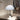 White table lamp on a reflective surface with abstract art in the background