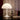 White lampshade on a table with a bottle, books, and an open book against a background of text.
