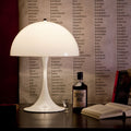 White lampshade on a table with a bottle, books, and an open book against a background of text.