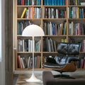 Modern interior with bookshelf, eames lounge chair, and white panthella floor lamp.