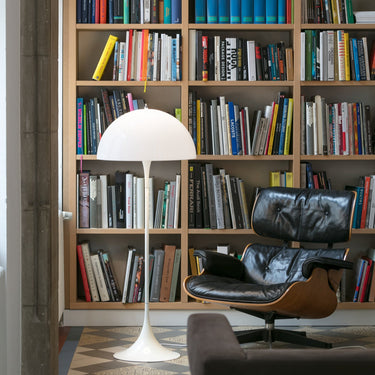 Modern interior with bookshelf, eames lounge chair, and white panthella floor lamp.