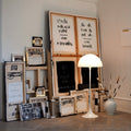 art studio interior with artworks, a  white panthella floor lamp, and decorative items on a wooden floor.