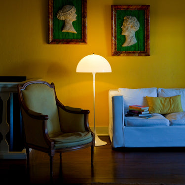 Living room with yellow walls, framed portraits, a lamp, and a sofa.