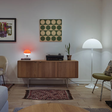 Modern living room with wooden furniture, panthella floor lamp, and wall art.