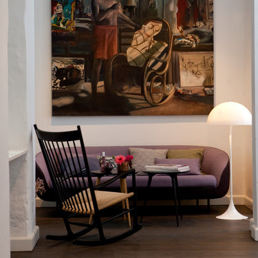 Living room with a painting on the wall, a rocking chair, and a lamp.