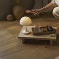 Person in a minimalistic room with a small table and lamp