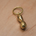 Gold peanut-shaped keychain on a wooden surface