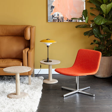 Modern living room with a brown armchair, red chair, and yellow wall abd tabke kano