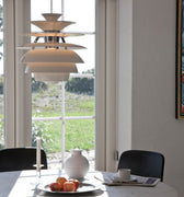 Dining area with a round table, chairs, and a large window with a view of greenery.