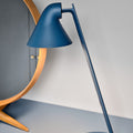 Blue desk lamp on a gray surface with a neutral background
