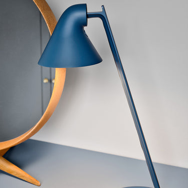 Blue desk lamp on a gray surface with a neutral background