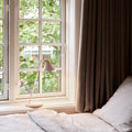 Window with brown curtain and pink lamp in a bright room