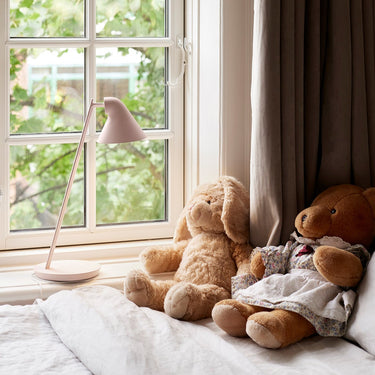 Two teddy bears sitting on a windowsill with a lamp and curtains in the background kids room lighting