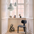 Modern interior with a black chair, decorative items, and pendant lights in a room with large windows.
