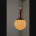 Video of a round glass pendant against a grey wall