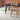 Dining table with chairs in a room with brick walls and leaf shaped rugs
