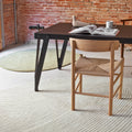 Dining table with chairs in a room with brick walls and leaf shaped rugs