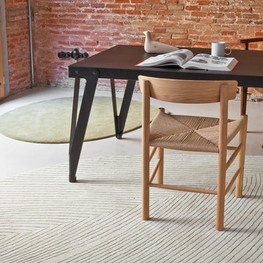 Dining table with chairs in a room with brick walls and leaf shaped rugs