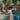 Outdoor setting with lounge chairs and rugs by a pool, surrounded by trees and buildings.
