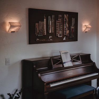 Wooden piano in a room with a wall painting and window