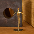Gold figurine of a dancer on a wooden surface with a textured background