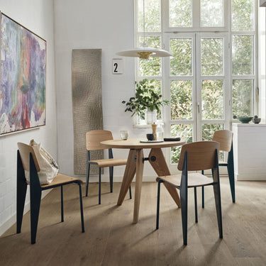 Modern kitchen and dining area with a large window, wooden floor, and jean prouve gueridon table and standard dining chairs sold at two enlighten