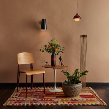 Modern interior with a wooden chair, small round table, and decorative items on a patterned rug.