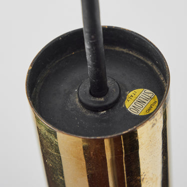 Close-up of a vintage stilnovo pendant with a black top and gold base on a white background with original label