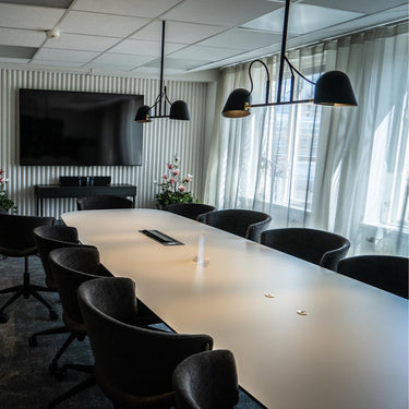 Modern conference room with a large table and chairs, featuring a TV on the wall.