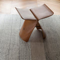 Wooden yanagi vitra stool on a textured rug