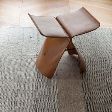 Wooden yanagi vitra stool on a textured rug