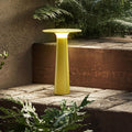 Yellow outdoor lamp on a stone ledge with plants around
